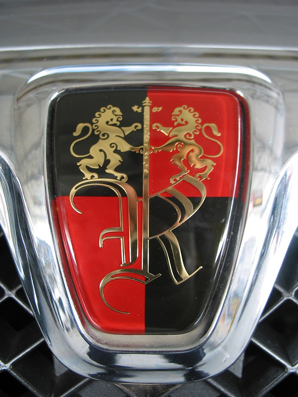 荣威品牌商标图案以"黑红盾牌"为底,两只站立的东方雄狮护卫华表,展现