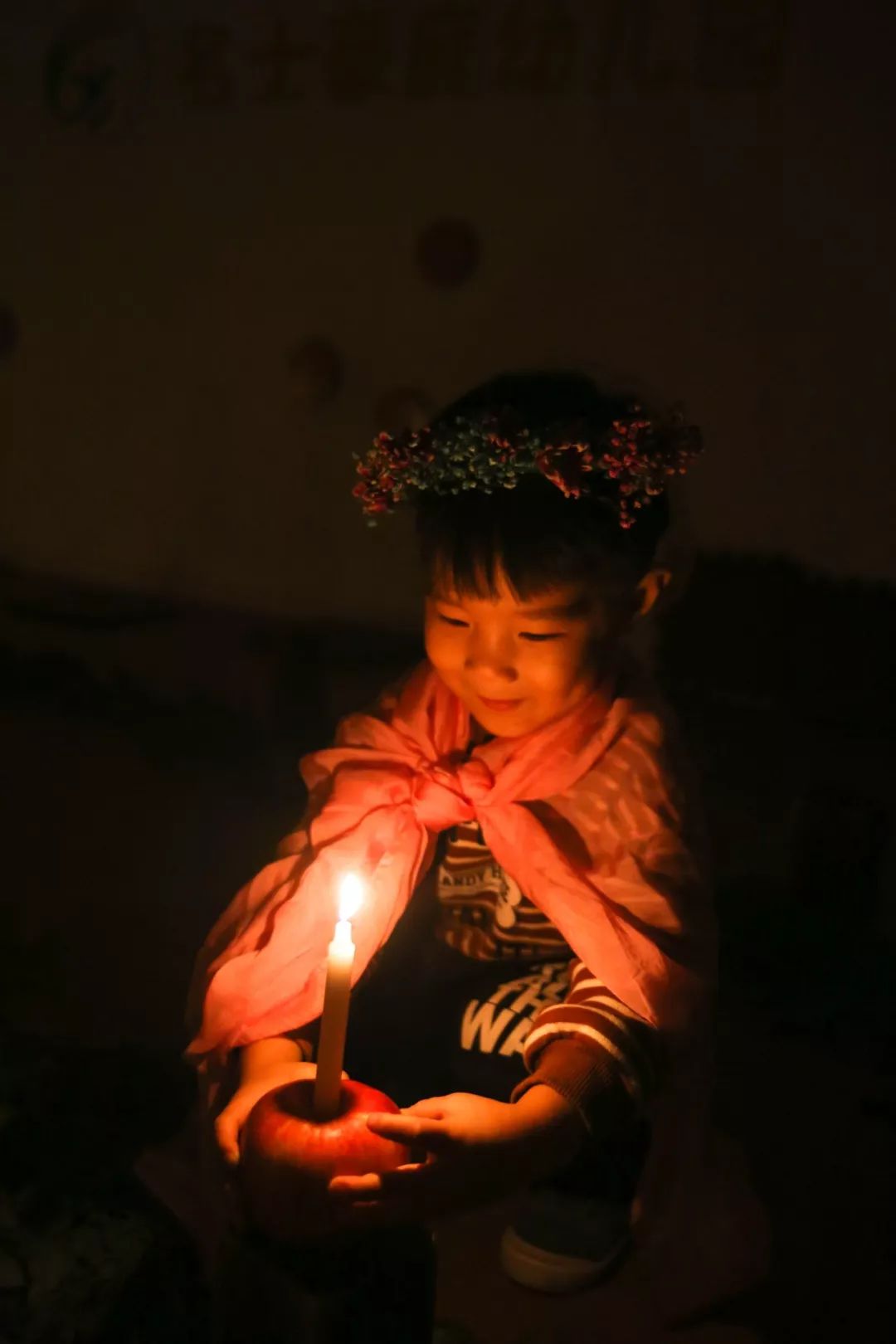 幼儿们怀抱蜡烛沿着婉转的枝叶走近中心的烛光,然后点燃.