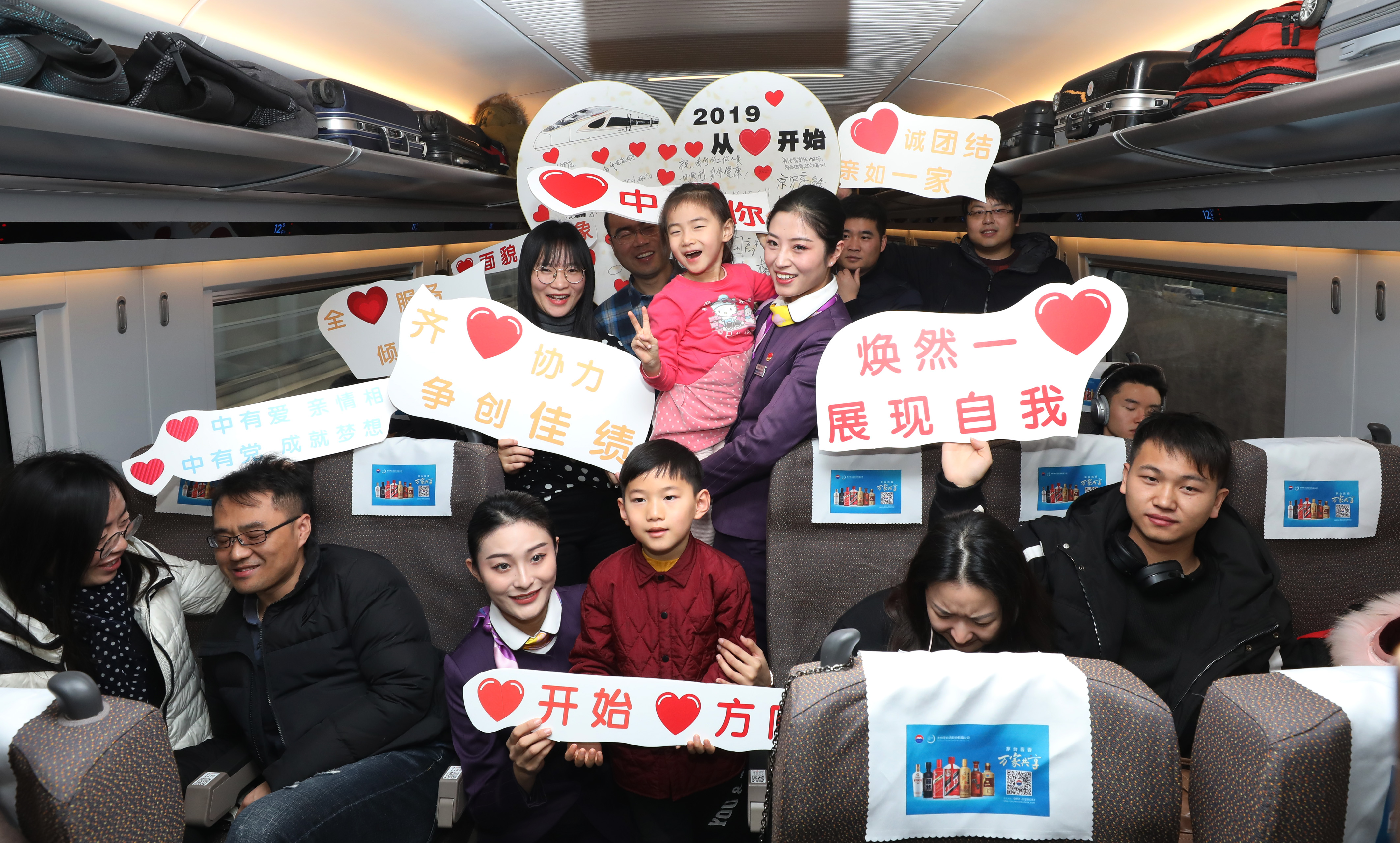 新的一年好愿景    12月30日,乘务员和旅客手举标语牌在车厢内合影