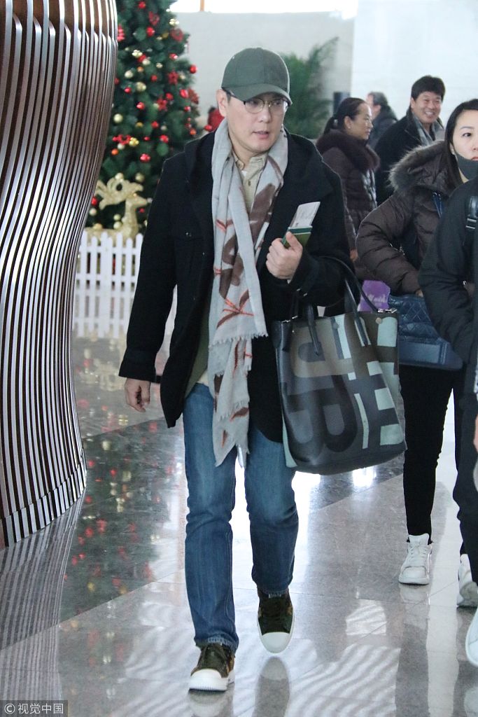 张信哲着装简便现身机场   戴鸭舌帽裹围巾显绅士风范