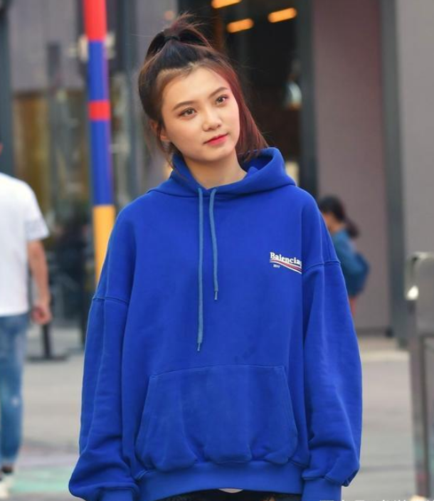 非常有气质的美少女,身穿一件蓝色的卫衣,颜色非常鲜艳亮丽,在人群中