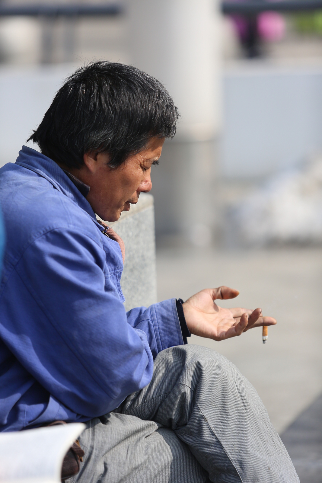 农民工火车站广场闭目"佛系"抽烟 只剩烟头也舍不得丢