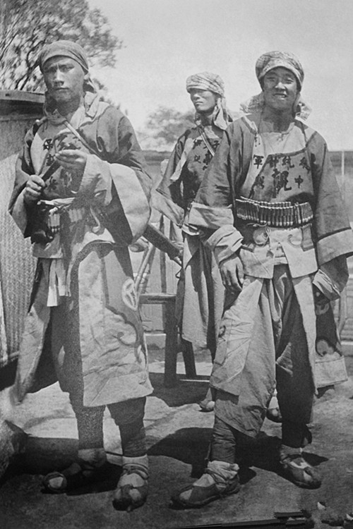 图为清朝末年,一名义和团士兵举着义和团的旗子.