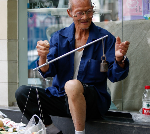 老伯坐在城里商店的橱窗一角,将家里的桃子挑到城里卖,老人称秤时的
