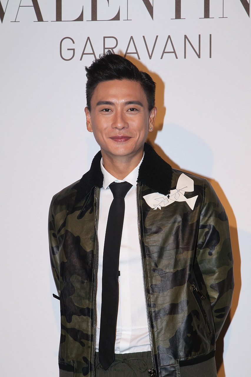 他穿着绿色外套,把棒棒糖放在脸边,微闭着眼睛