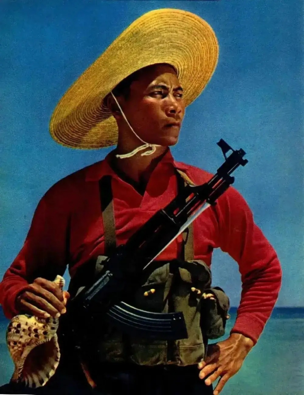 上世纪70年代,西沙群岛一名民兵的照片,头戴草帽,斜挎冲锋枪,右手拿着