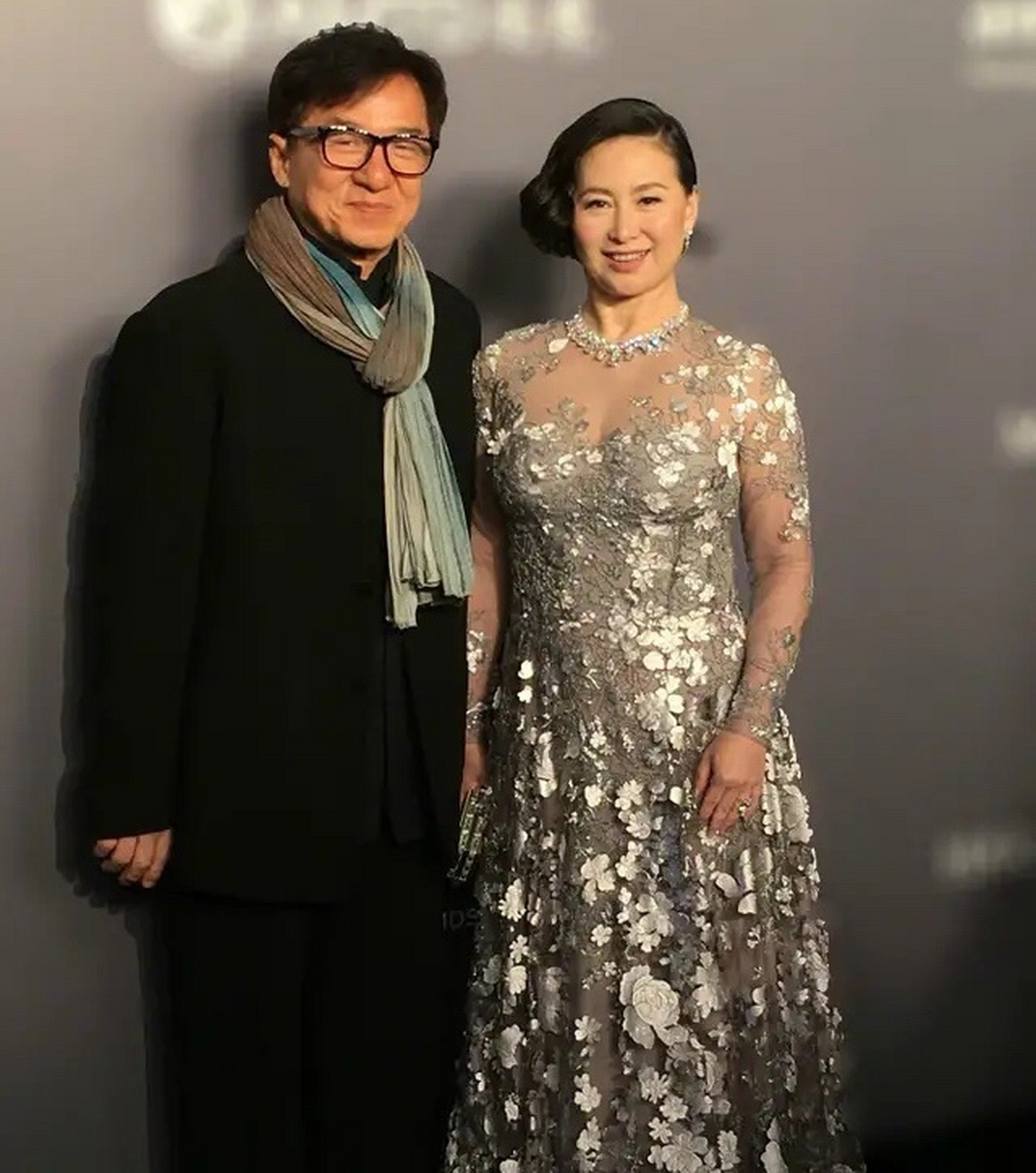 成龙在何超琼身边很绅士,直接把手背在身后,大方自然