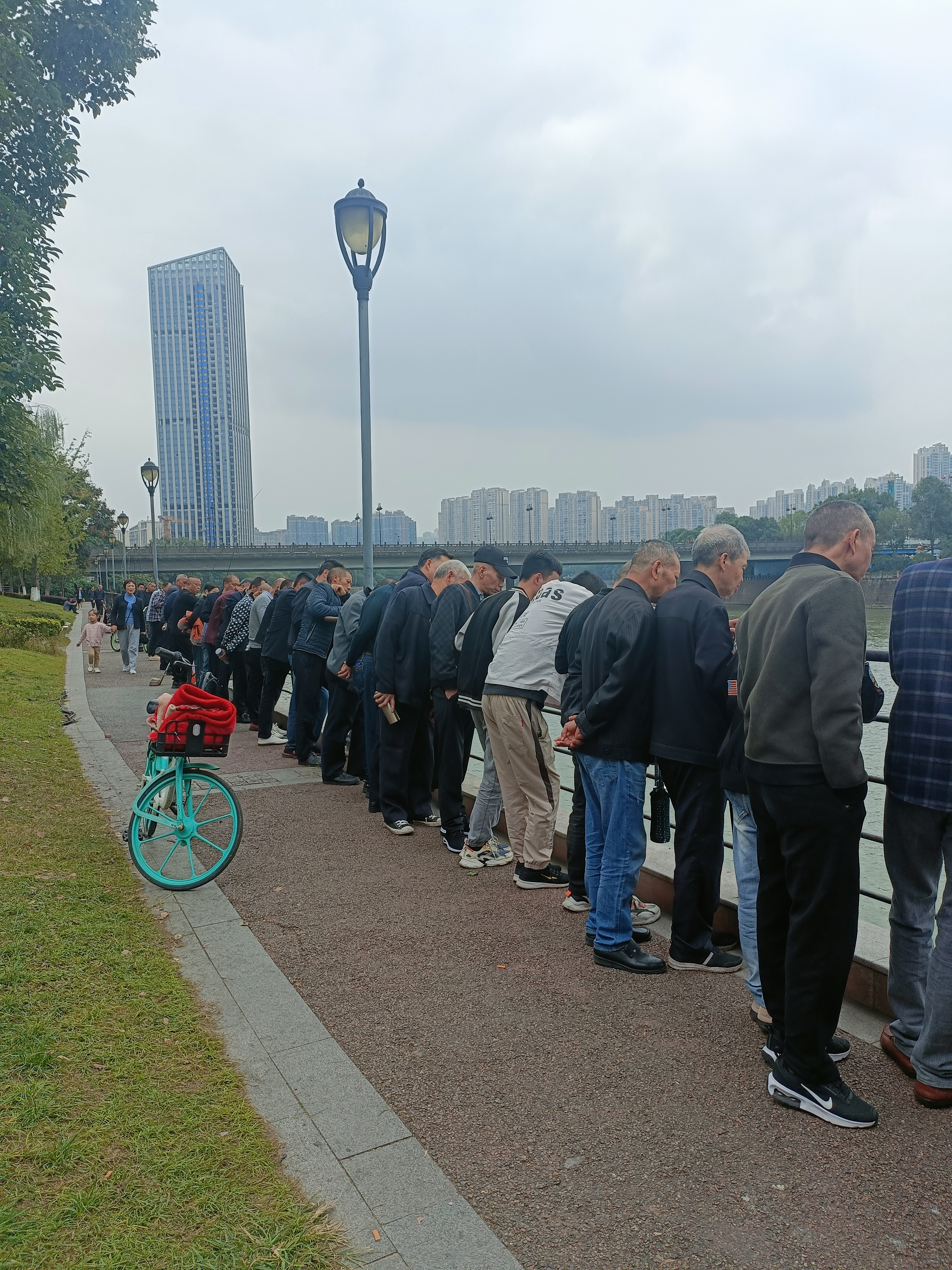 返回途中,远远看到江边站了一排人,他们个个围杆低头