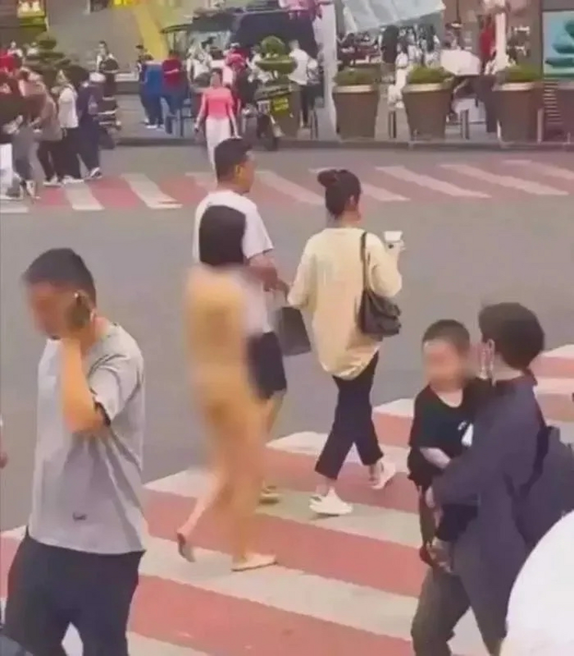 年轻女孩在市中心被激怒从而裸体行走,男朋友提着衣服跟在后面,路过的