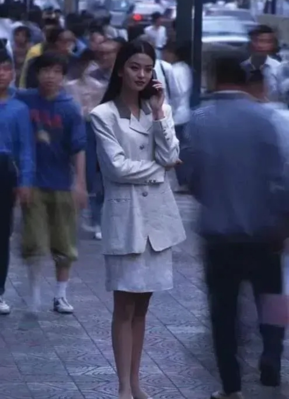 90年代上海街头一位打扮时尚的女孩,她一身职业装显得干练,手里的