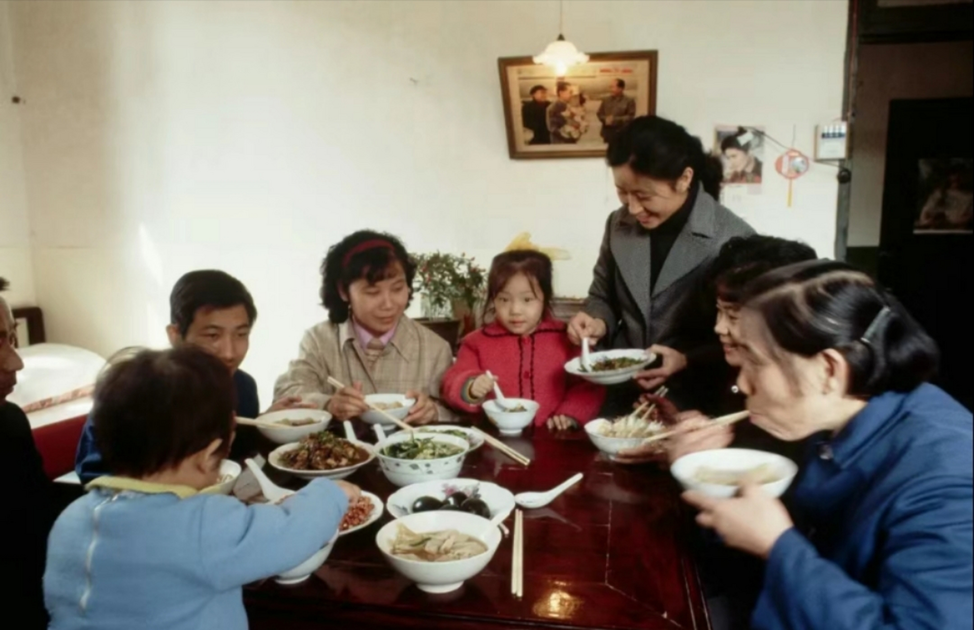 二十世纪八十年代,某城市一大家子在吃饭,那时候,吃饭不分家,一大家子