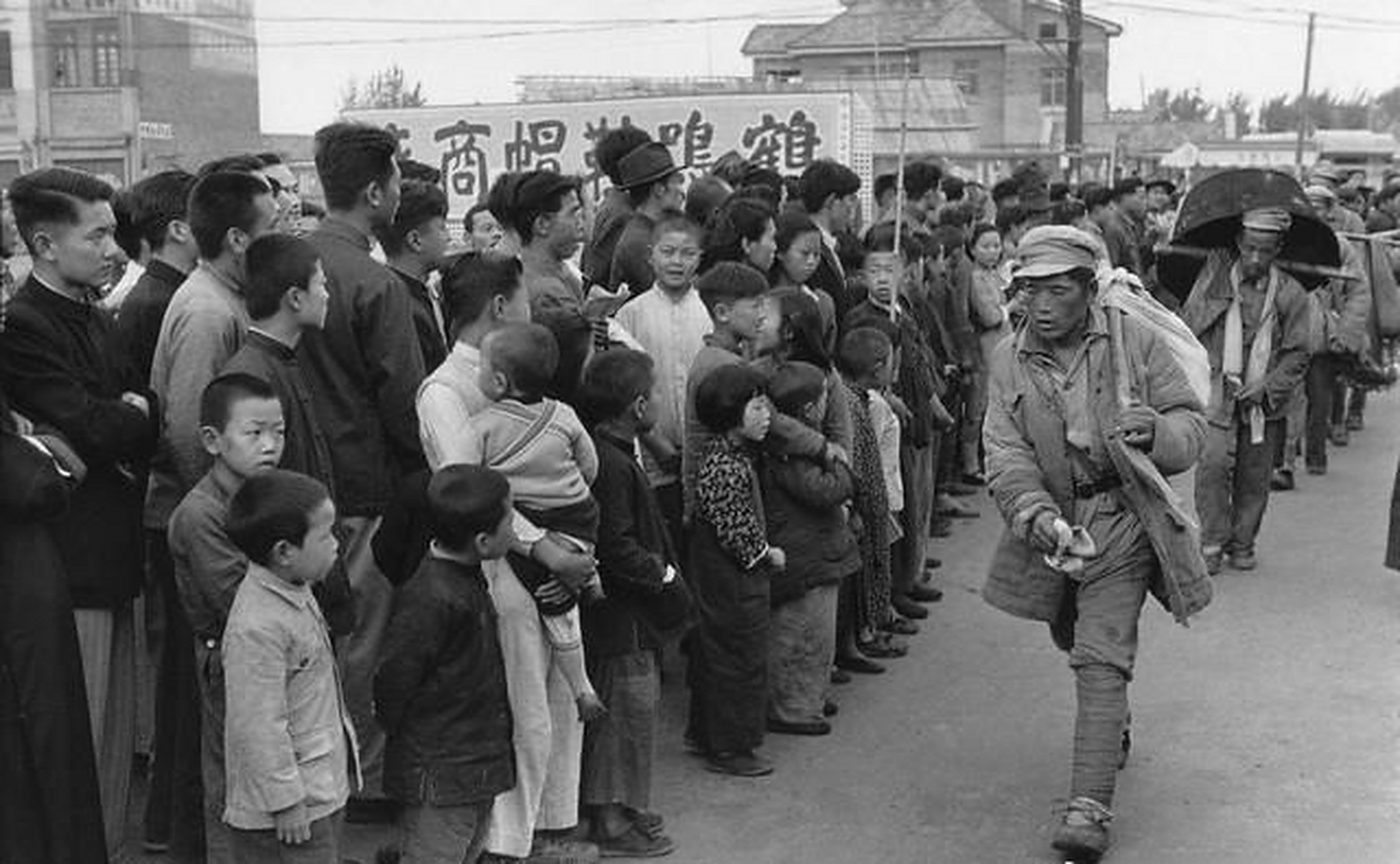 1949年4月,刚刚参加完渡江战役的解放军战士,在市民的注视下进入南京