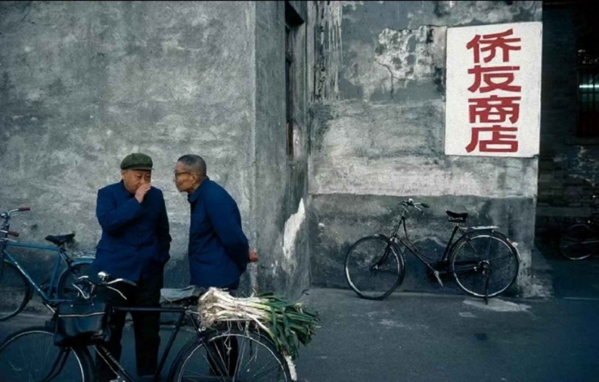 1985年,北京街头,用自行车驮着大葱的男子,正在与朋友聊天!