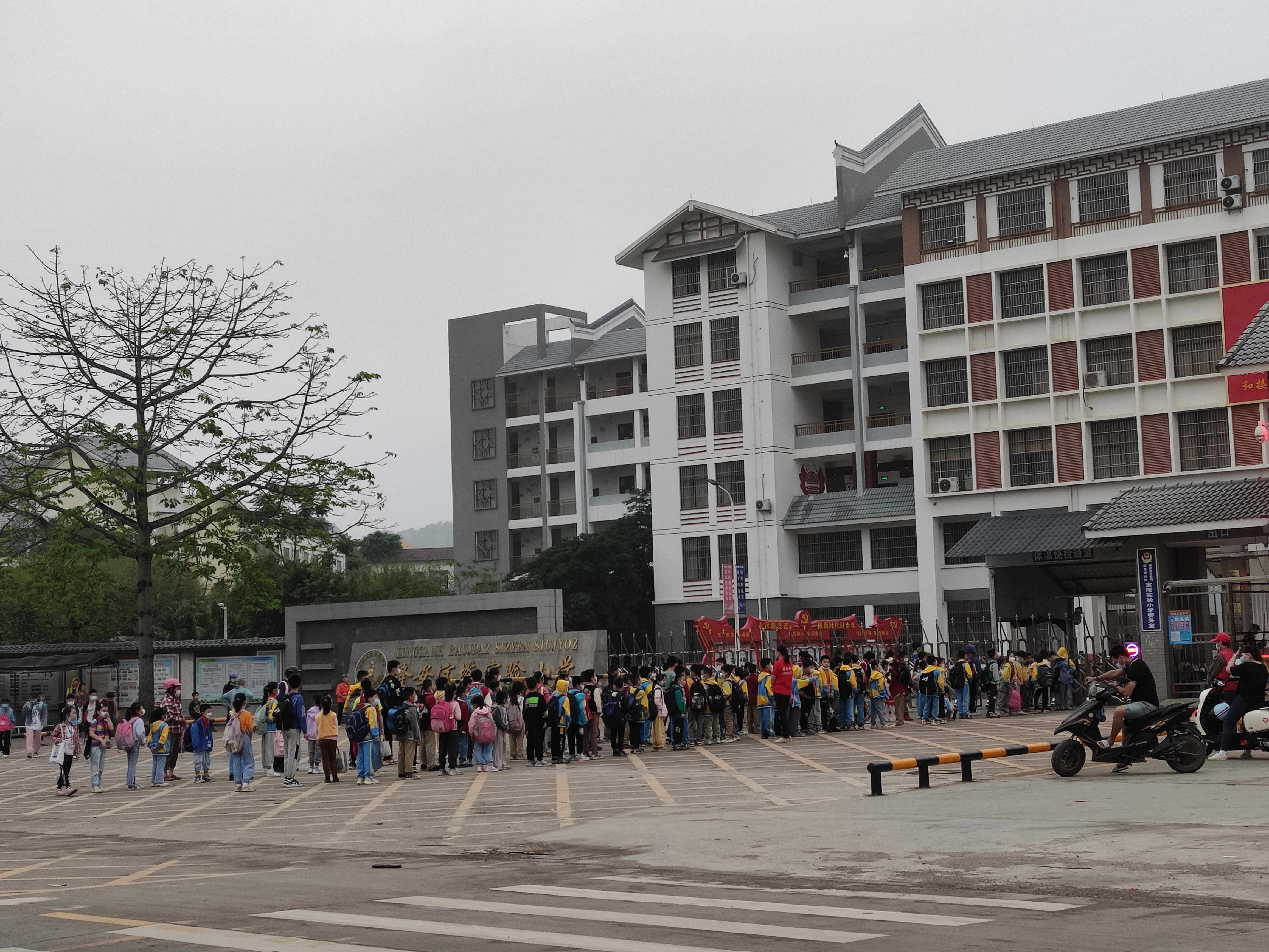 路过一个学校门口时,很多小学生和家长早早的在