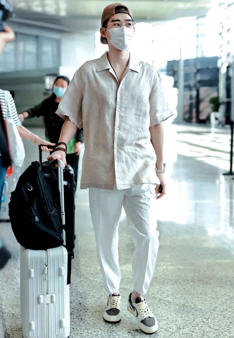 照片中,张翰身穿米色衬衫,搭配白色裤子,清秀随意