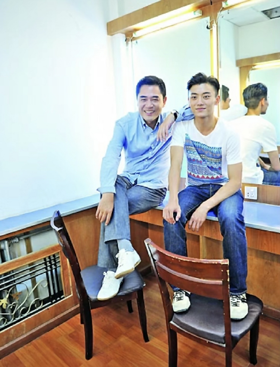 老戏骨陈宝国与儿子陈月末的合影.父子俩人并排坐在化妆间的桌子上.