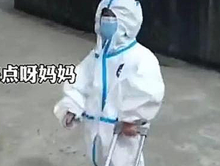 江苏南京:小朋友穿着防护服走在前面拉着行李箱