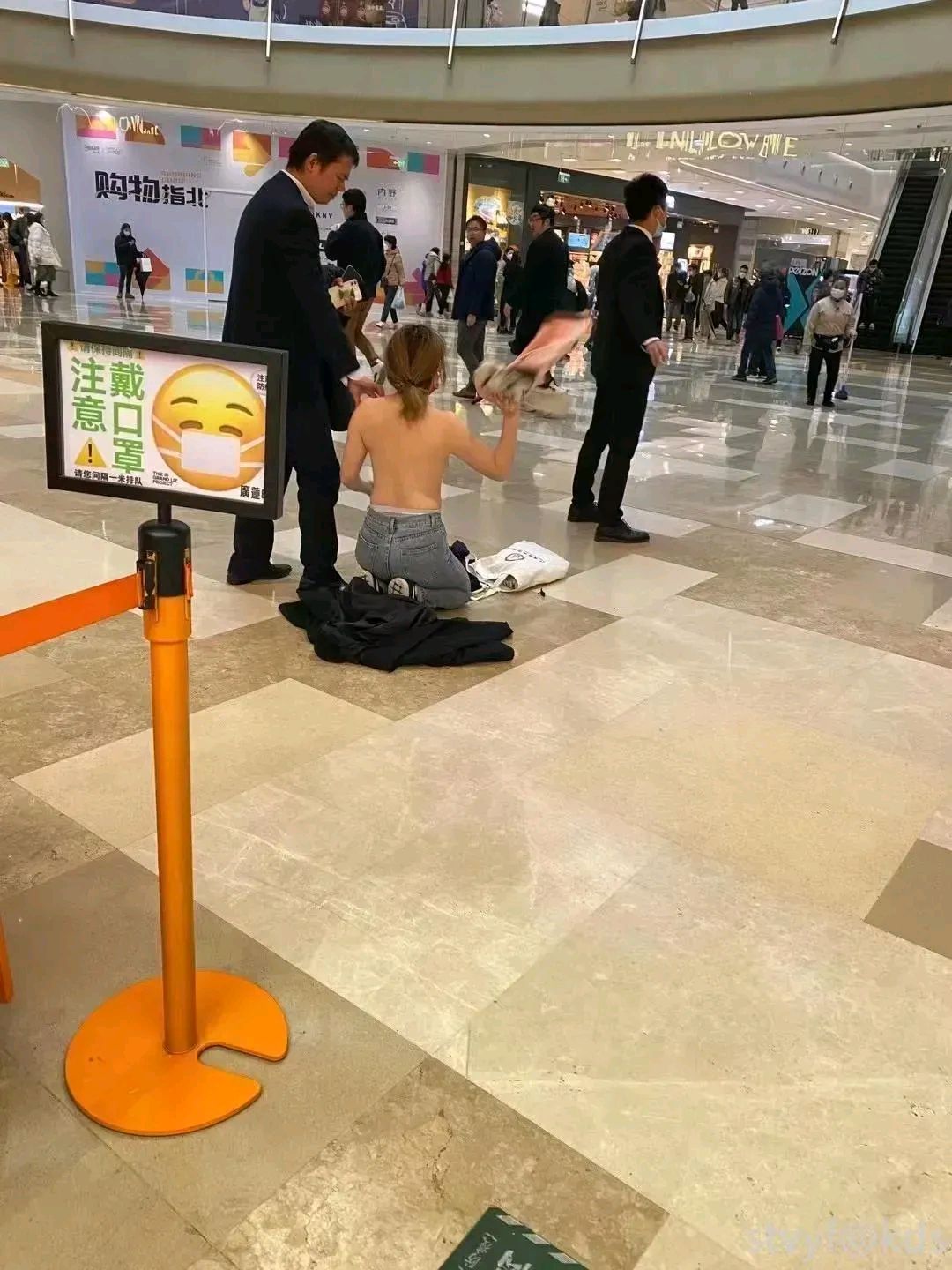 一女子赤裸上身跪在商场内不知道是什么事情让她这么激动不顾形象