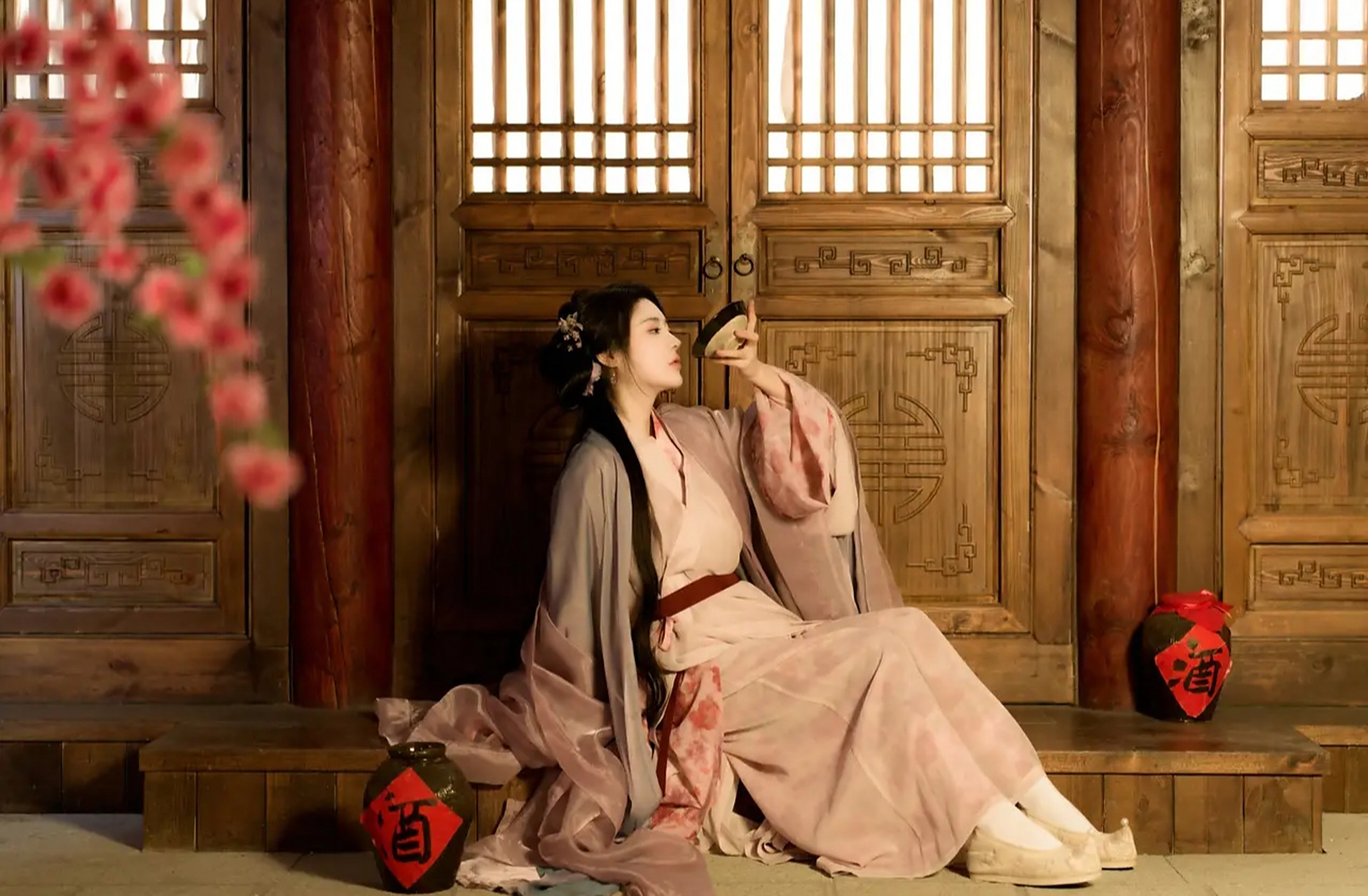 照片中,莫寒一袭古装,桃花盛开时,坐在台阶上,独自饮酒,不知为哪般.