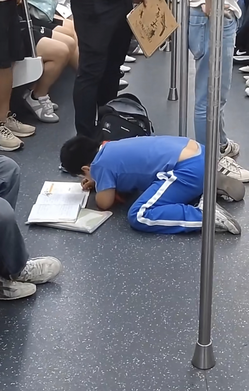 深圳地铁上一位正在写作业的孩子,周围的大人应该让