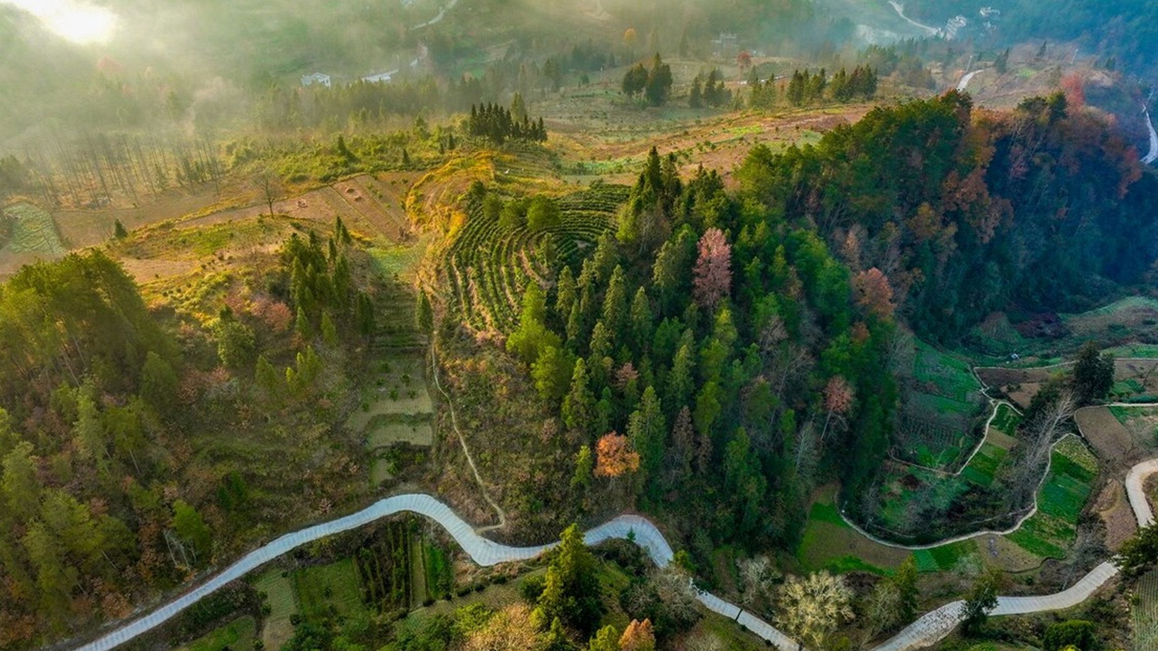 重庆酉阳,雪融后的丁市镇,清晨的第一缕阳光透过云层洒下,薄雾在山间