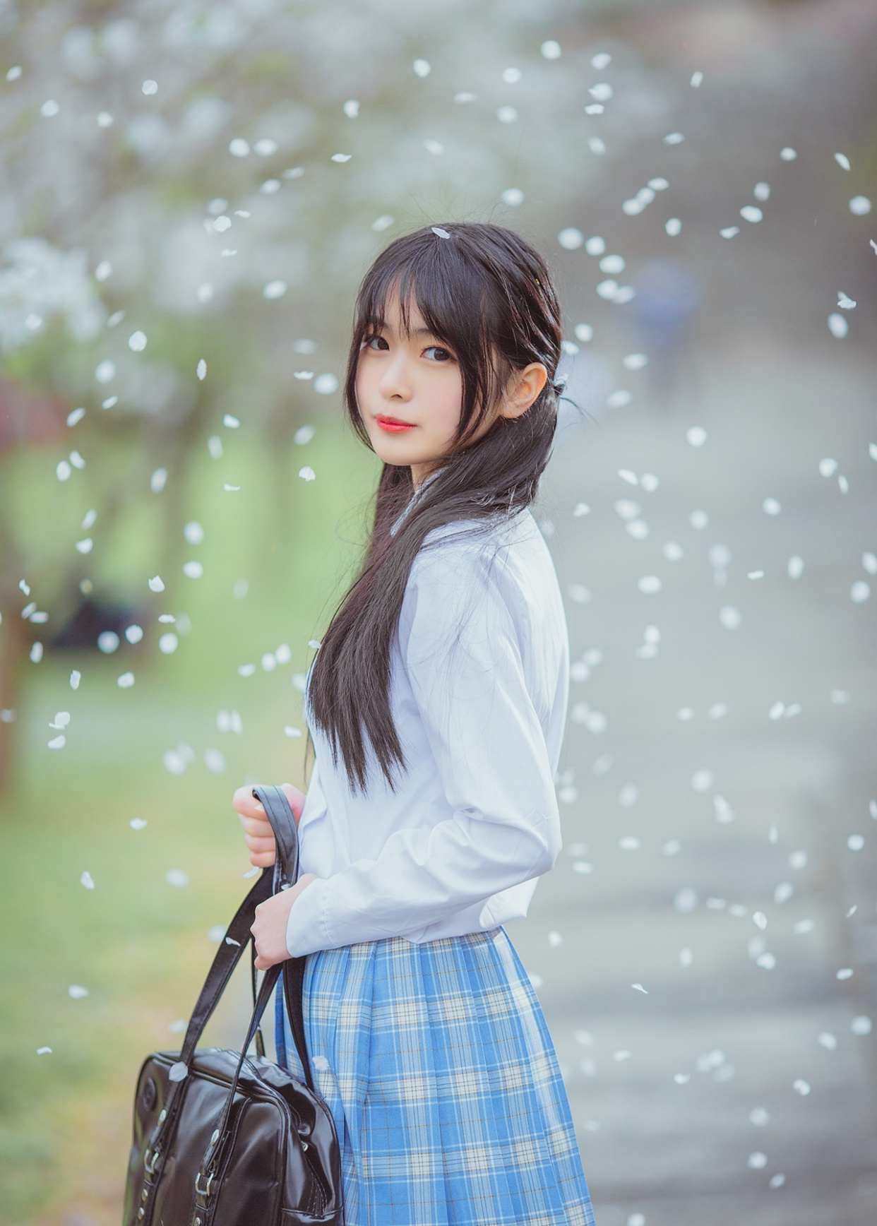 一头黑色长发绑成双马尾的jk少女,手捧着飘落的花瓣,像捧着思念