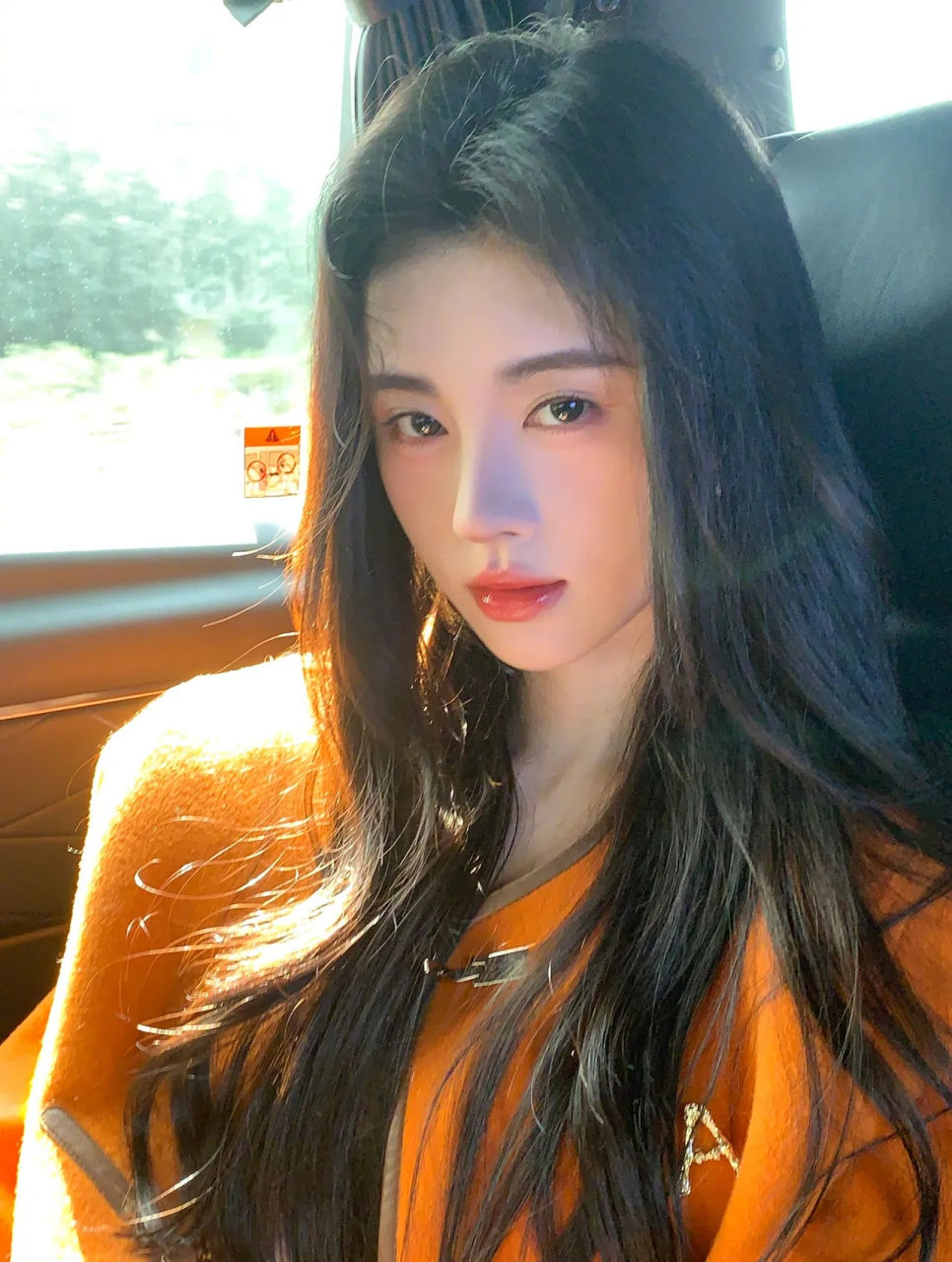 美女鞠婧祎,一袭橙色小西装,坐在车后座,她微笑着向镜头鞠躬,精致的