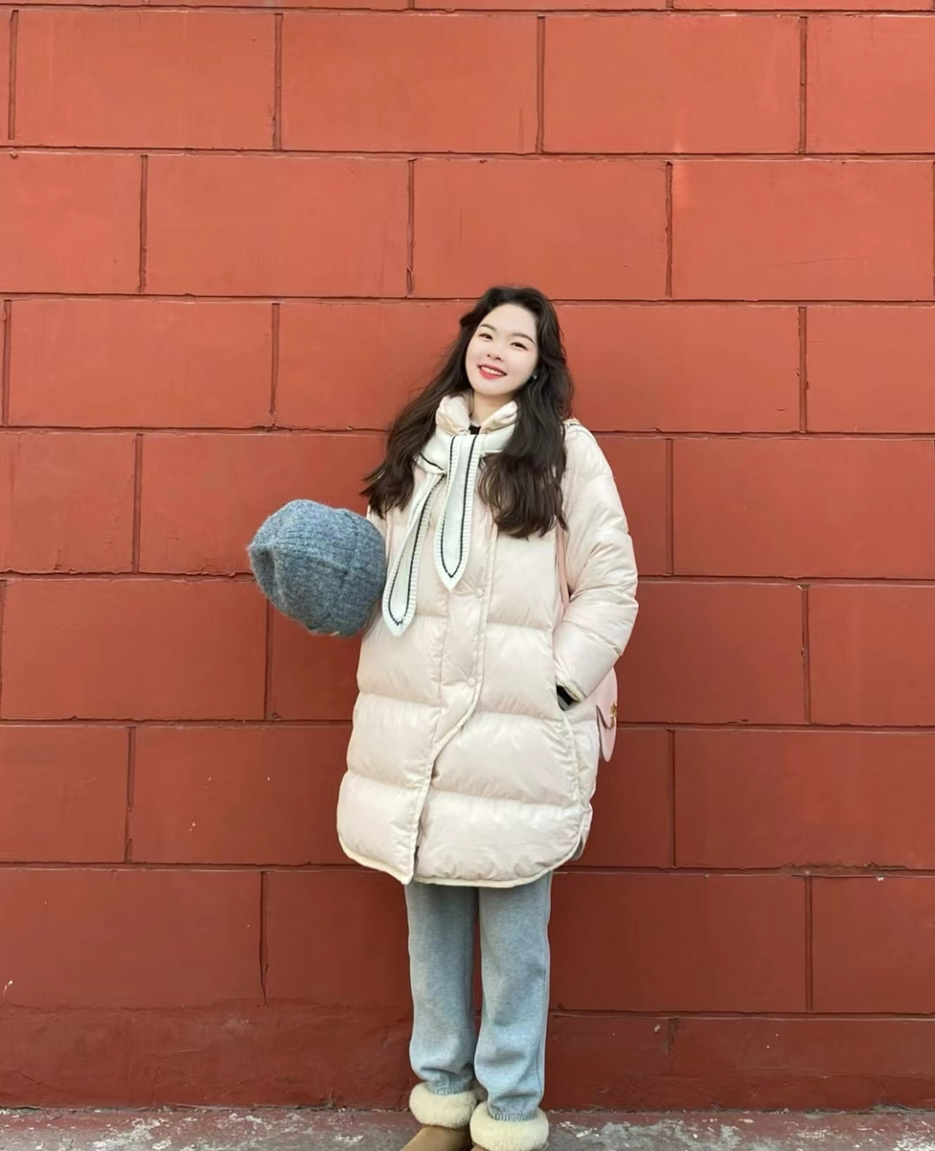 宽松设计的杏色羽绒服搭配蓝色牛仔裤,脚踩雪地靴,展现出一种遮肉