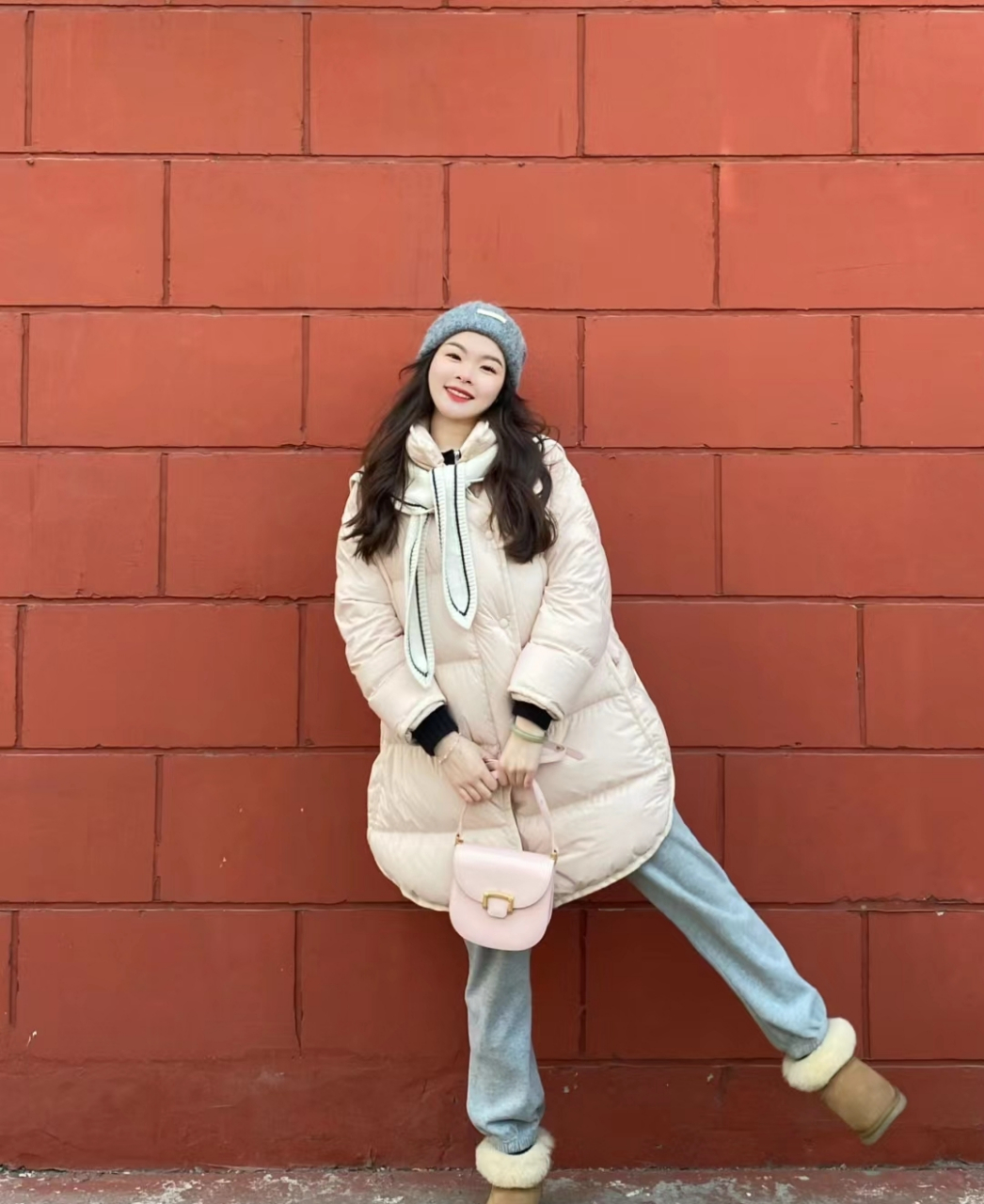 宽松设计的杏色羽绒服搭配蓝色牛仔裤,脚踩雪地靴,展现出一种遮肉