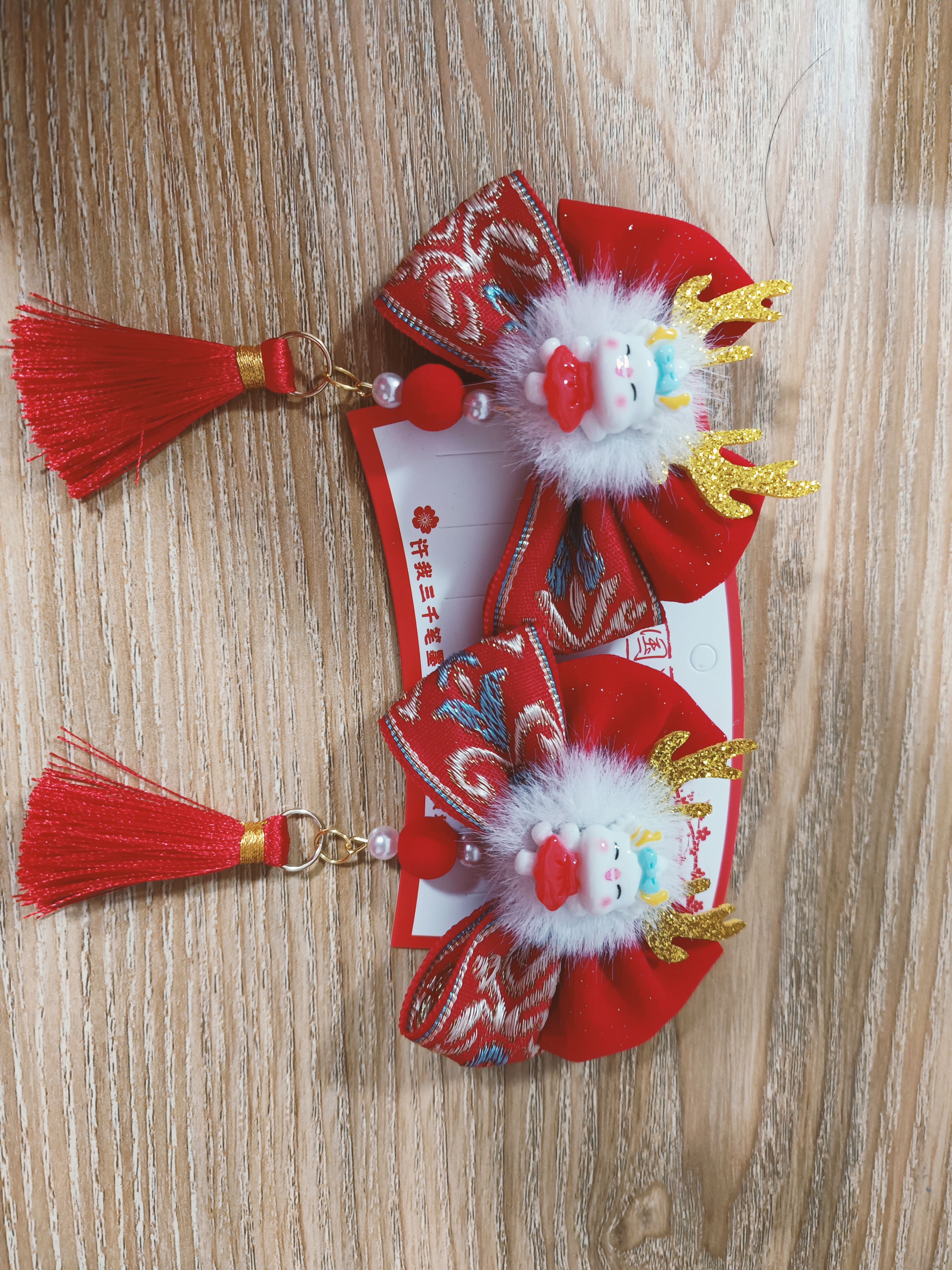 大红的蝴蝶结,轻盈流动的流苏,可爱的小龙人!再配上美美的拜年服!