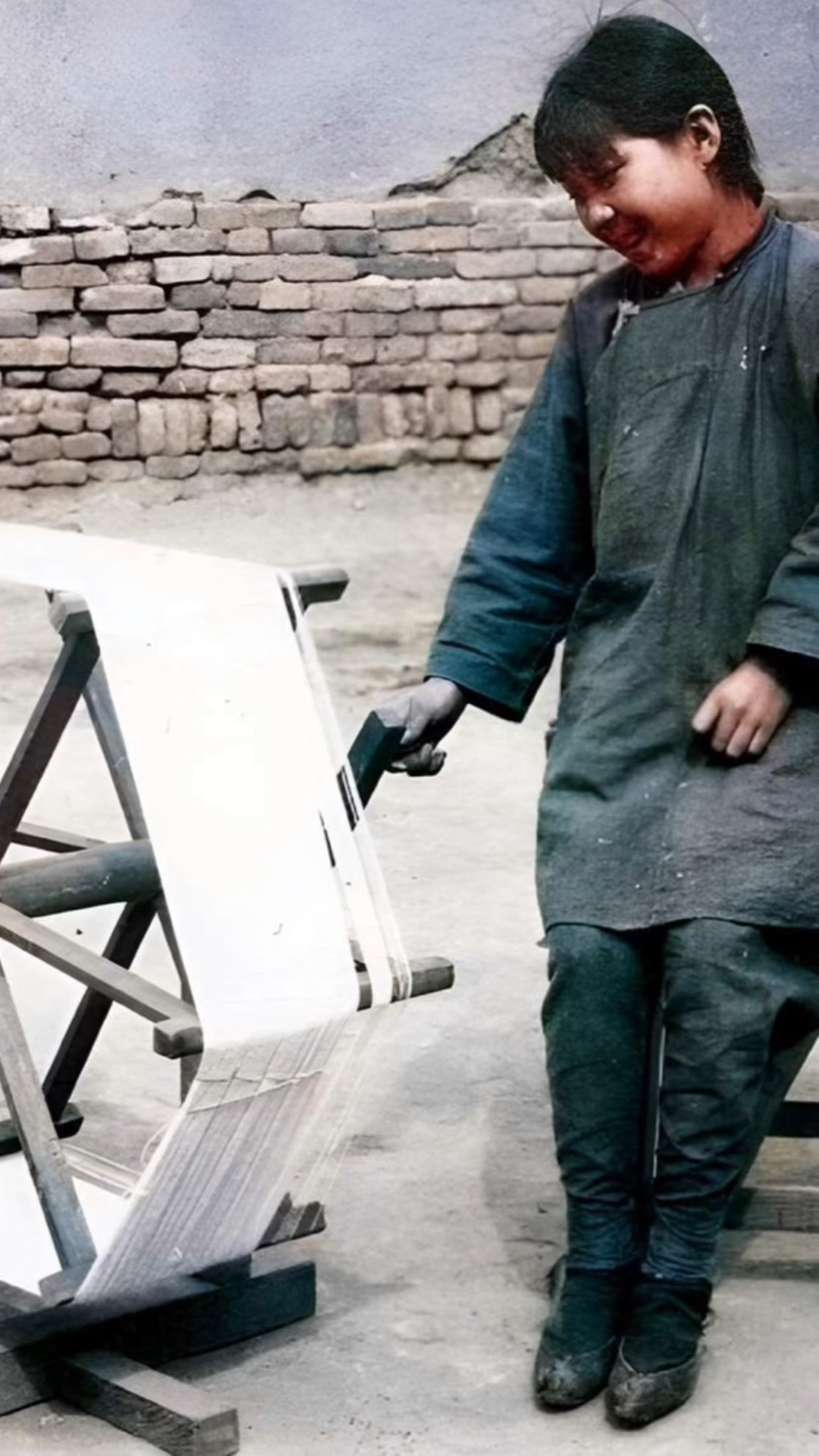 民国时期临近春节的腊月,一位女子坐在长凳子上熟练的纺线