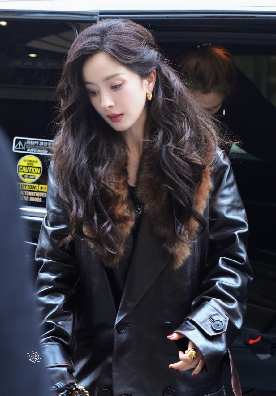 杨幂身穿绒毛领黑皮大衣,脚踩银色高跟鞋,戴着墨镜,搭配大波浪卷发