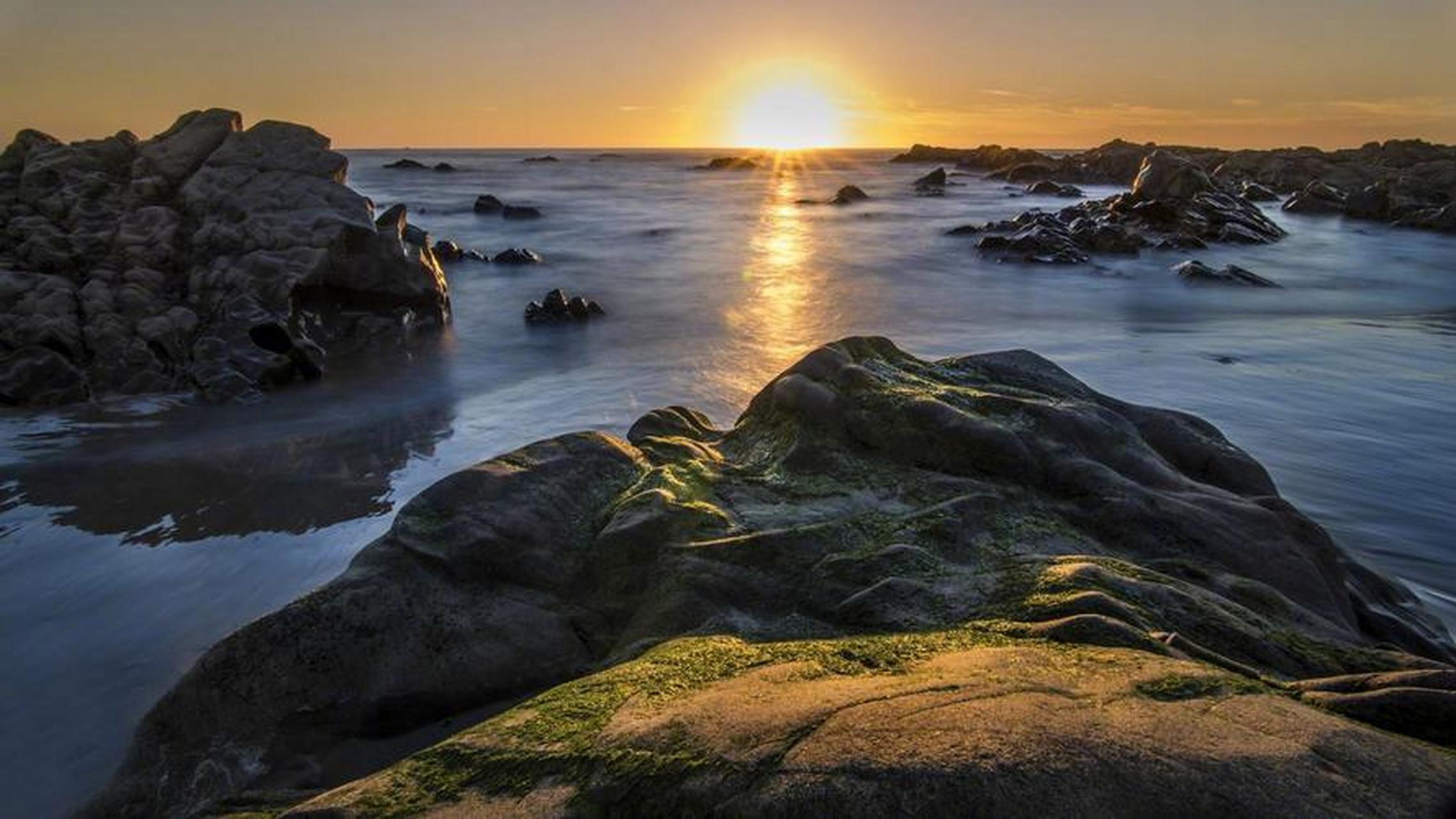 当黎明的第一缕阳光照射在海边,海水穿校在礁石群中,景色怡人.
