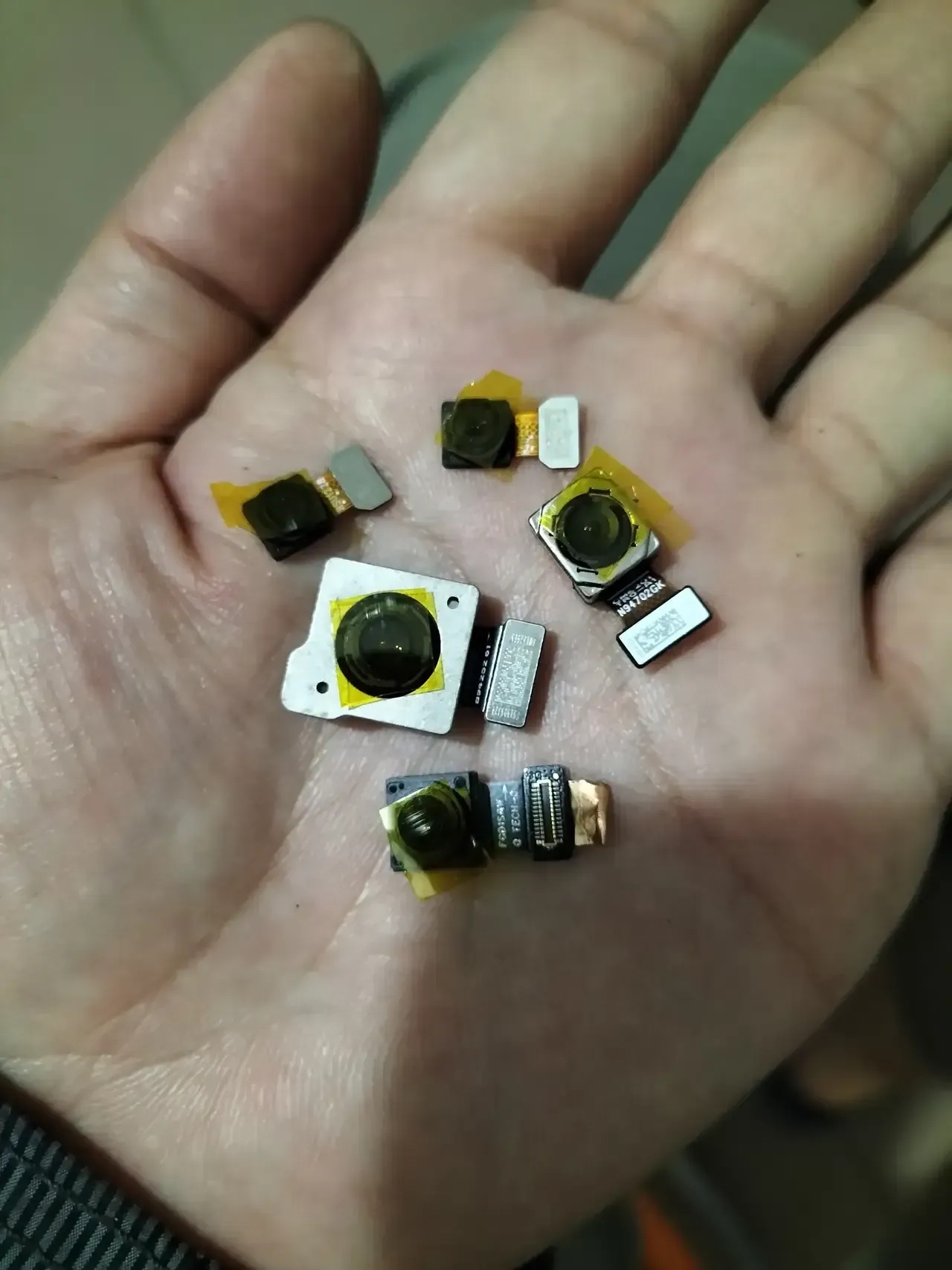 手中握着一堆被拆解下来的手机摄像头,每一个都拥有令人惊叹的几千万