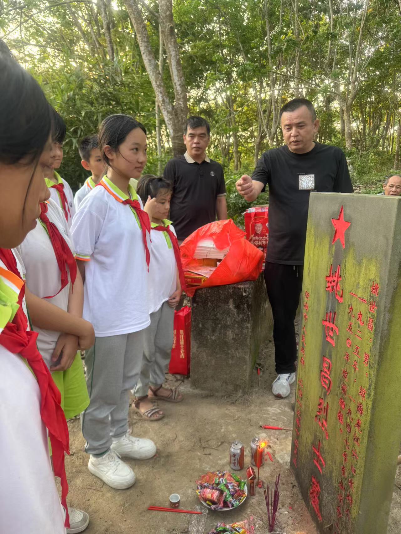 大家一起动手清理墓地及周围的杂草接着摆上新鲜的水果然后向烈士