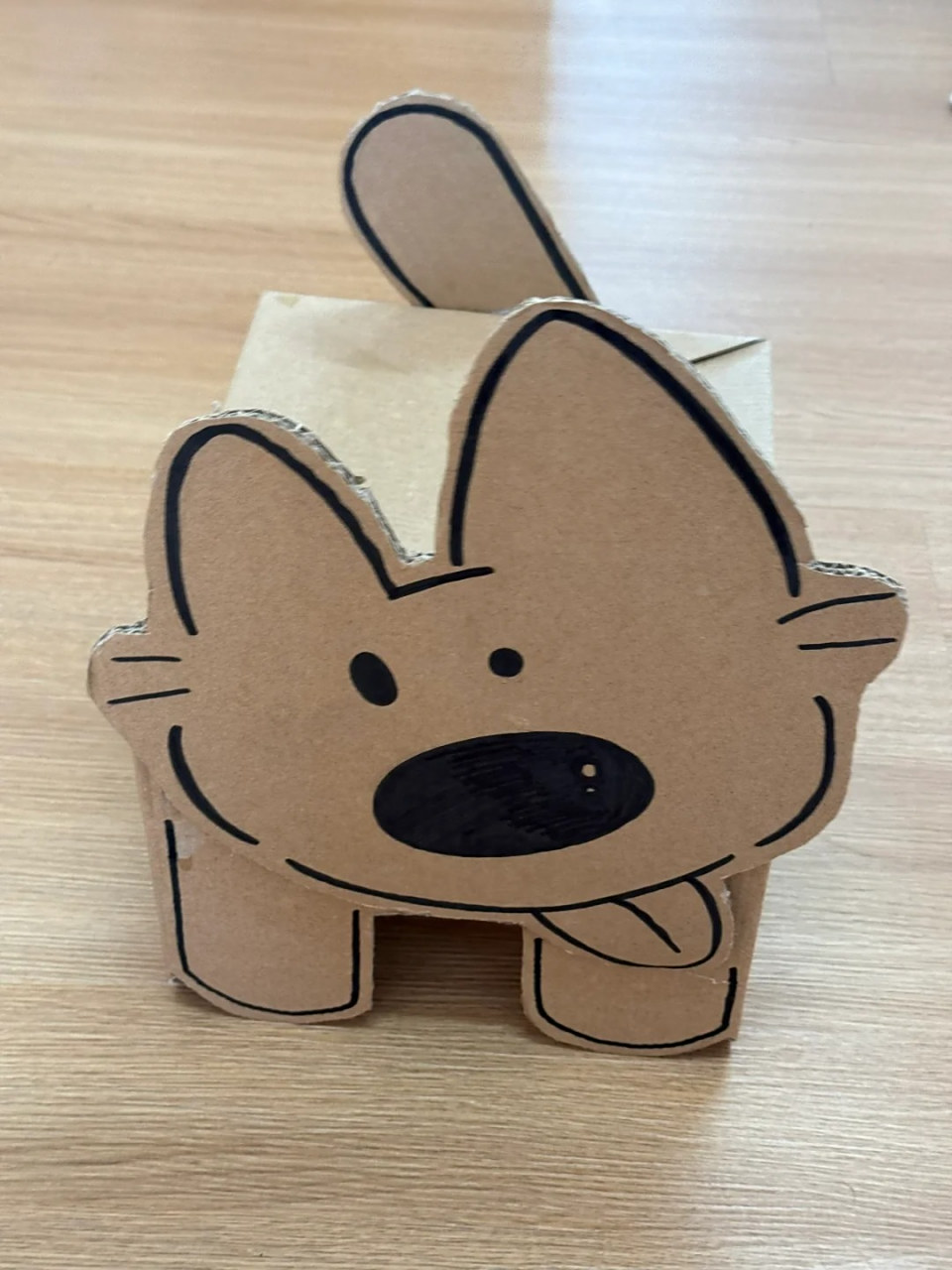 废弃牛奶盒翻过来露出卡其色一面 在纸板上画好小狗的脸 尾巴 纸盒做