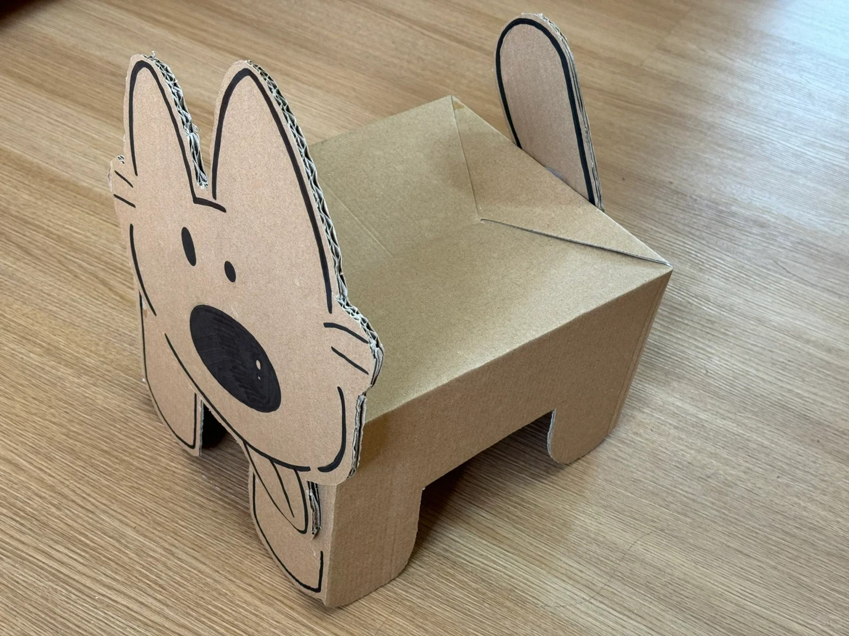 废弃牛奶盒翻过来露出卡其色一面 在纸板上画好小狗的脸 尾巴 纸盒做