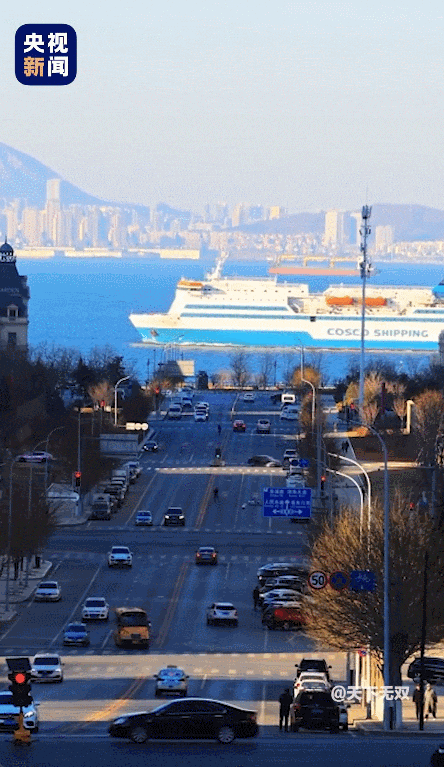 一条宽阔起伏的路,尽头是蔚蓝色的大海,蓝天,轮船,缓缓前行的车辆和行