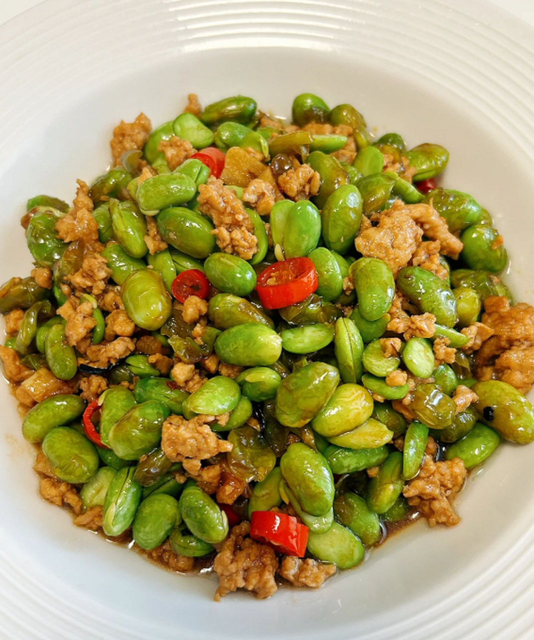 制作时先焯熟毛豆,再炒制肉沫,最后与料汁和小米辣翻炒.