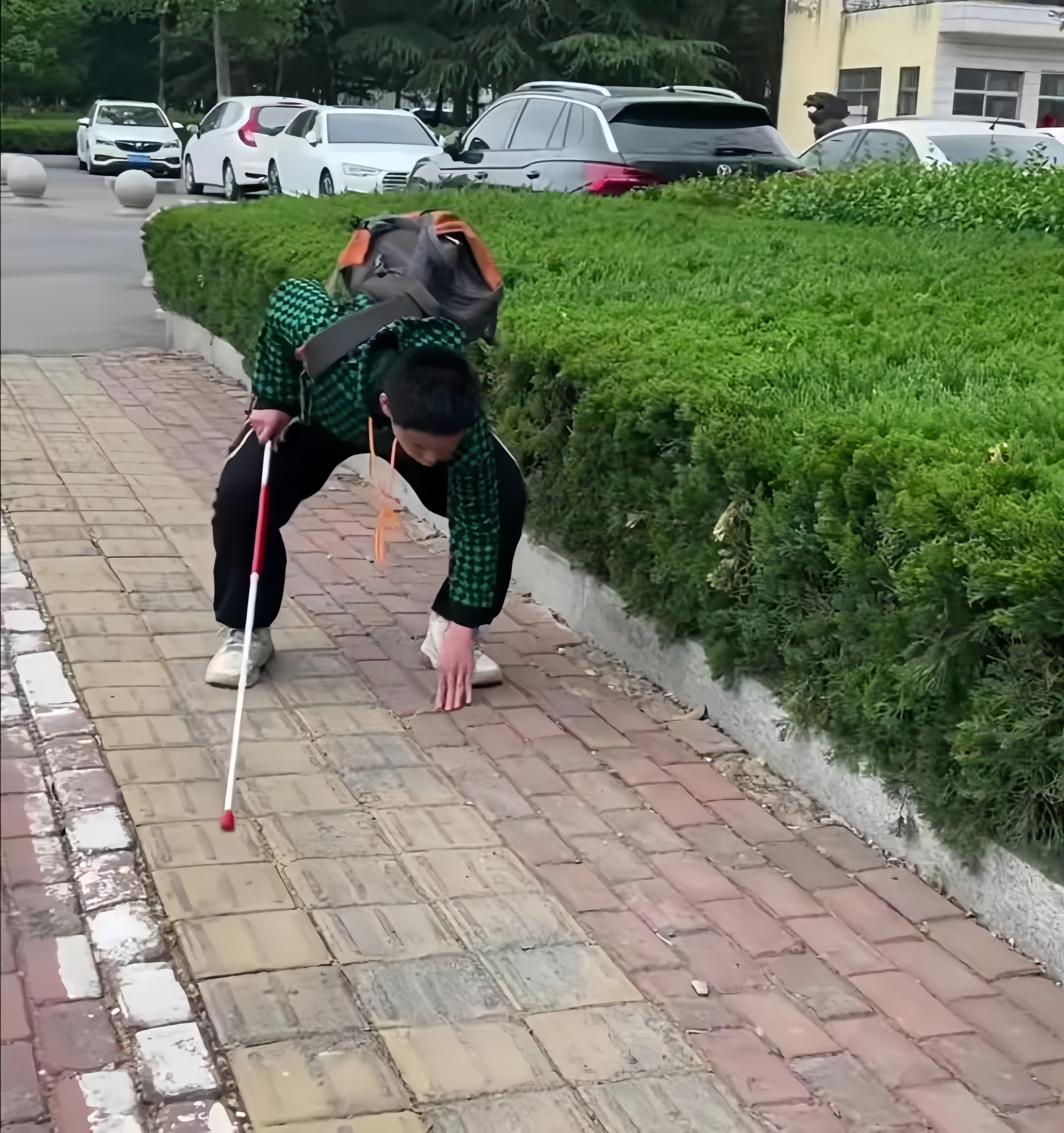 在儿子后面,儿子的一举一动都看在眼里,当看到儿子弯腰伸手去摸盲道时