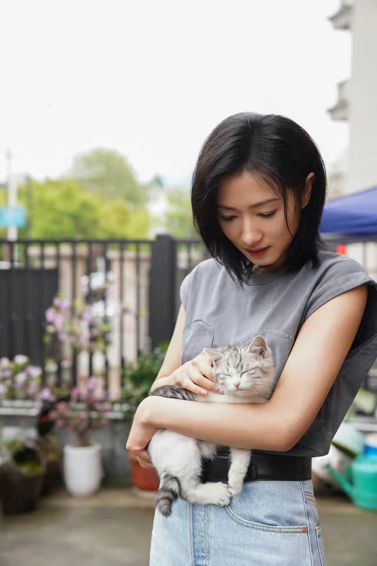 照片中,万茜身穿灰色连肩袖圆领t恤,搭配白色高腰直筒长裤,脚踩一双