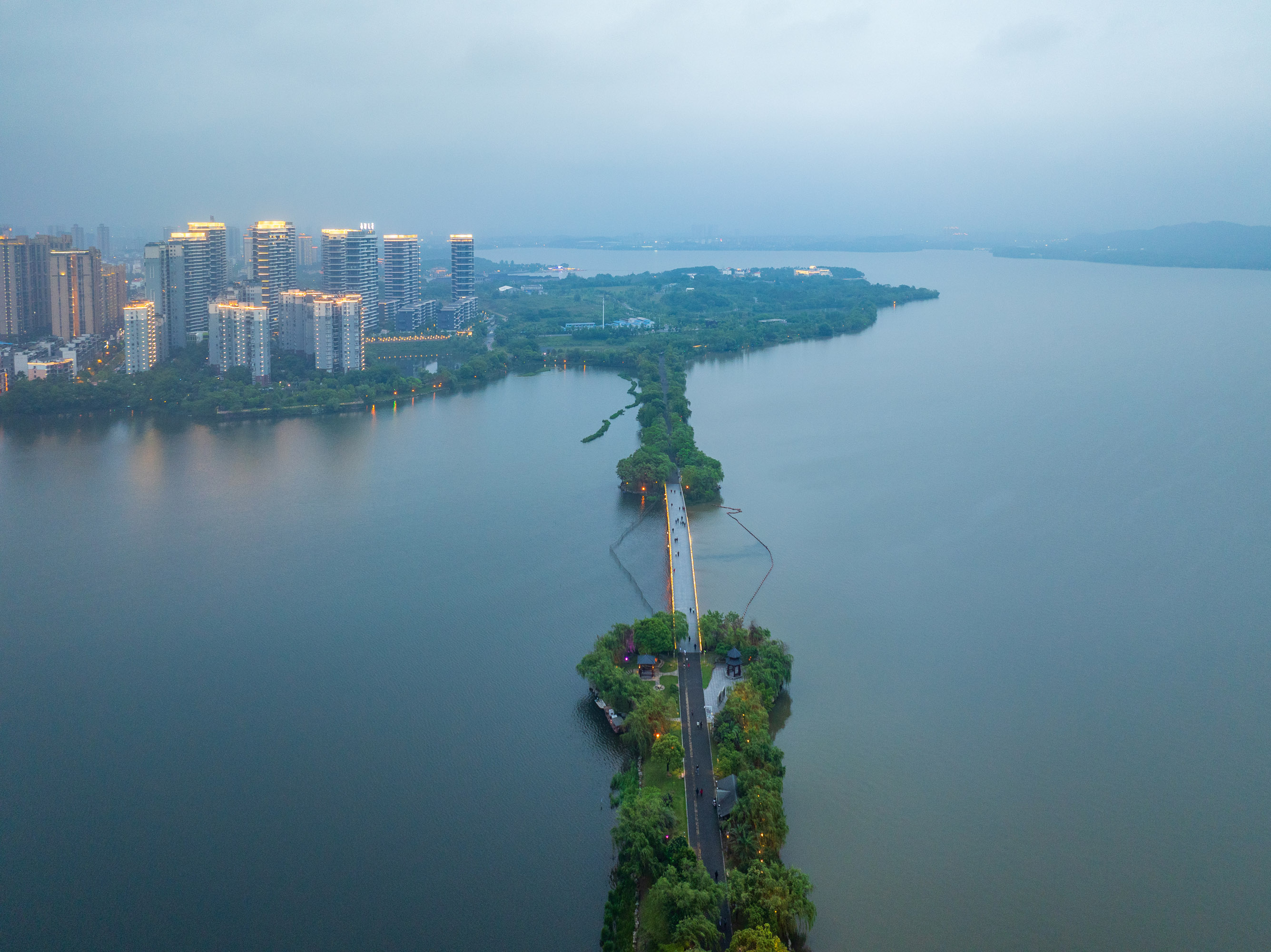 航拍湖南岳阳洞庭湖南湖风景区夜景,湖面平静如镜,岸边灯光璀璨夺目.