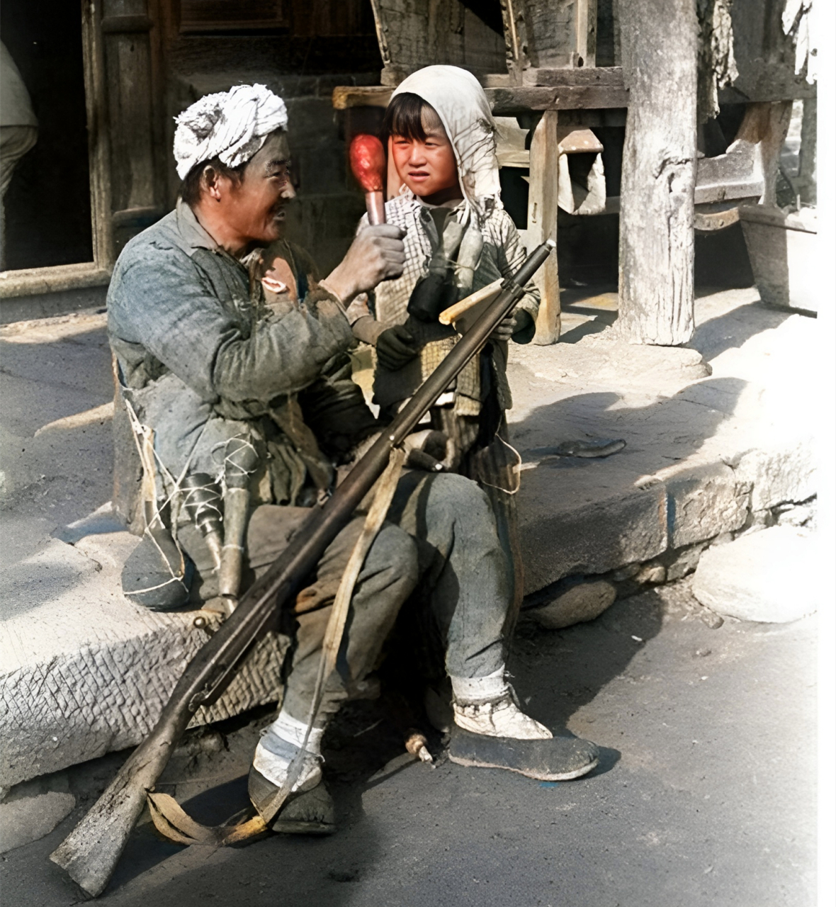 1944年,抗战时期的延安,一位民兵老人正在向一位小孩展示儿童手榴弹.