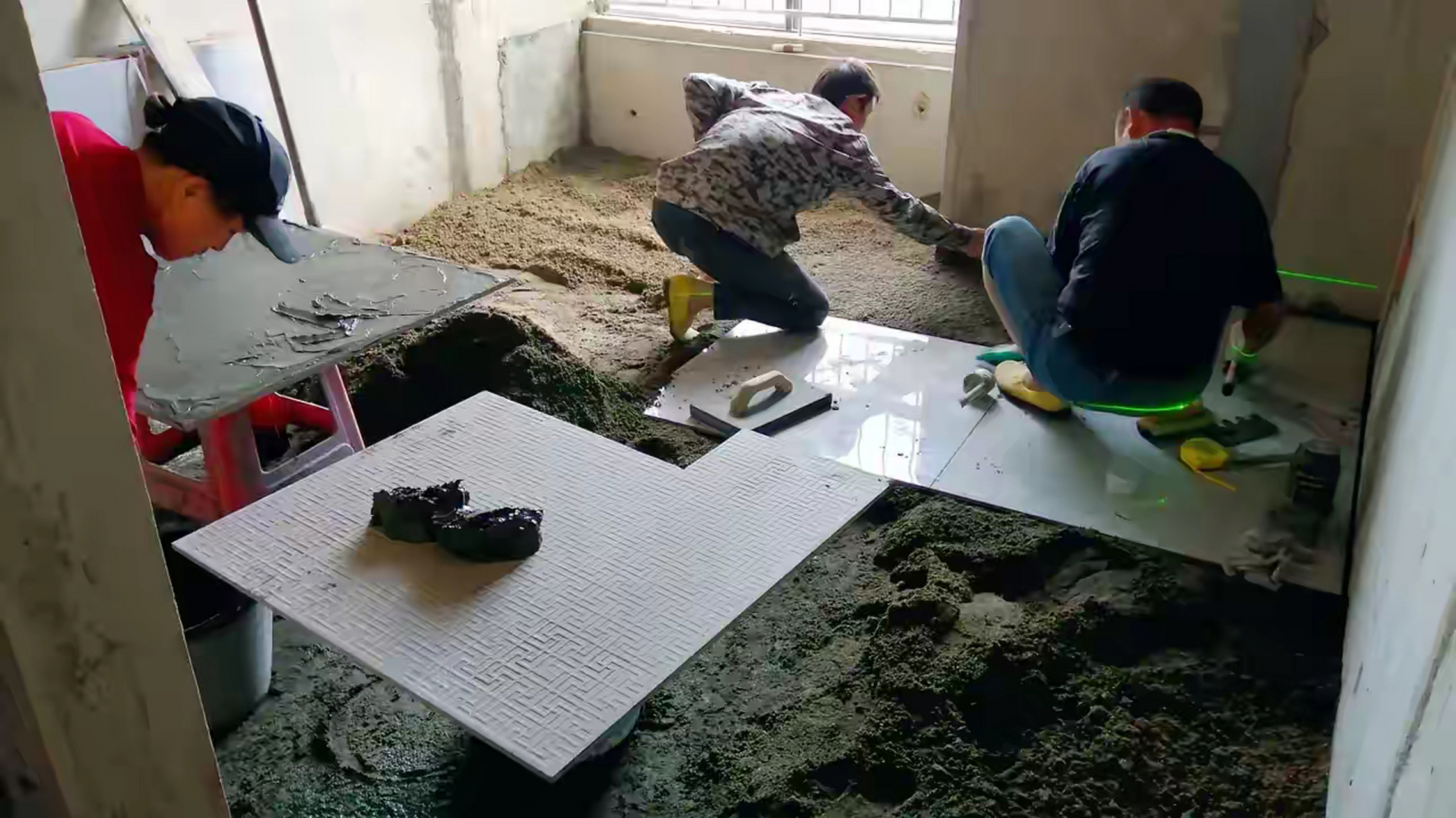 新房进入铺砖阶段,贴砖师傅是一家三口,可以说是子承父业,他母亲做