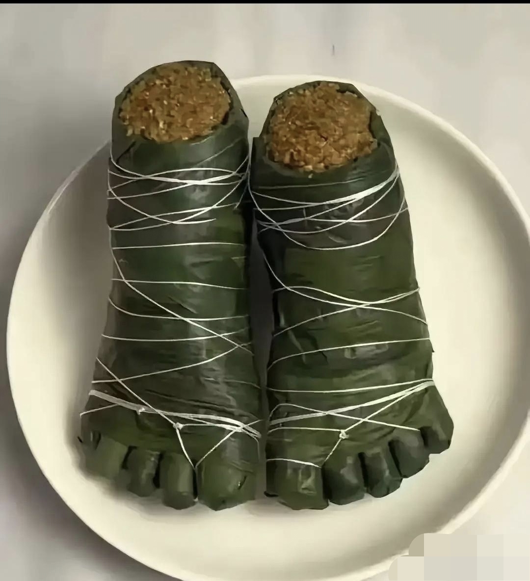 每个脚形粽子都用白色的线仔细地缠绕紧紧的,模仿了传统粽子的捆绑