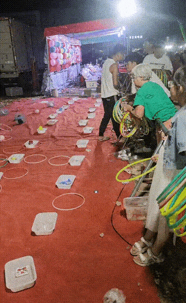 现场中有一小伙子忙套圈圈,老太太忙递圈圈给儿子去套,看来这小伙子