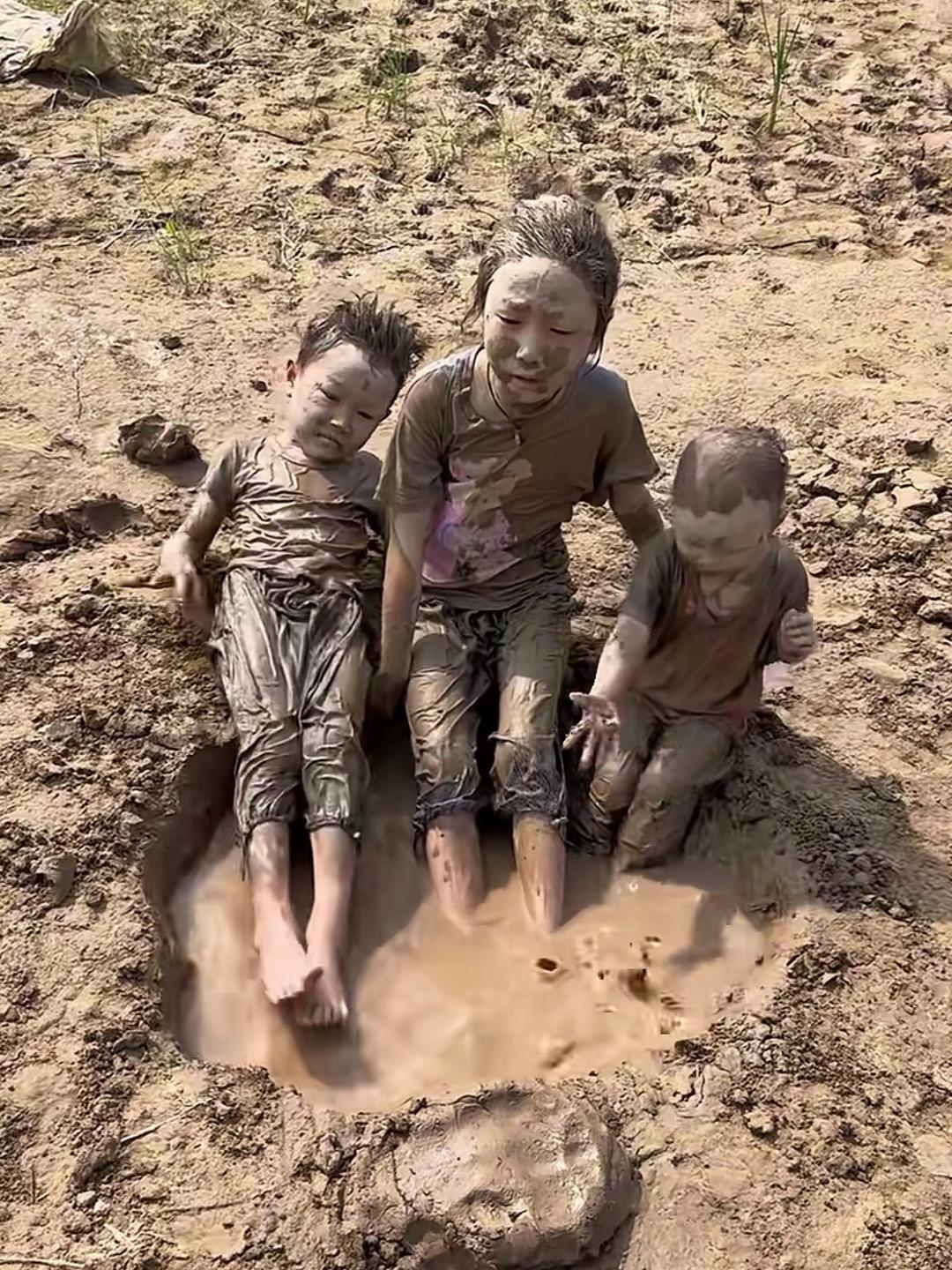 三个小屁孩在泥潭水里玩耍,玩累了就爬上来,躺在水潭边上晒太阳,无忧