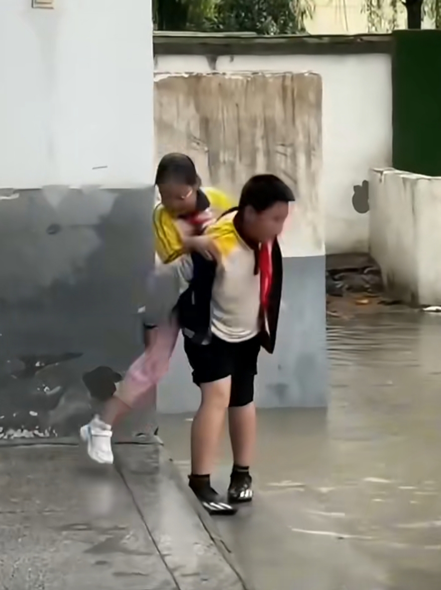 校园里因下雨导致通往女厕所的道路积满了水时,男孩见状主动上前背着