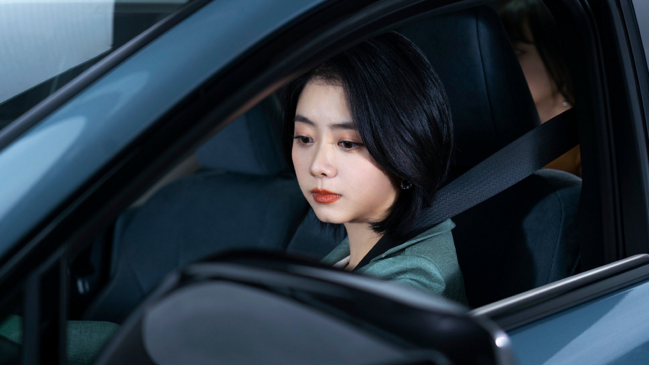 谭松韵身穿青绿色外套,短发造型搭配黑色墨镜,坐在车里的样子,非常有