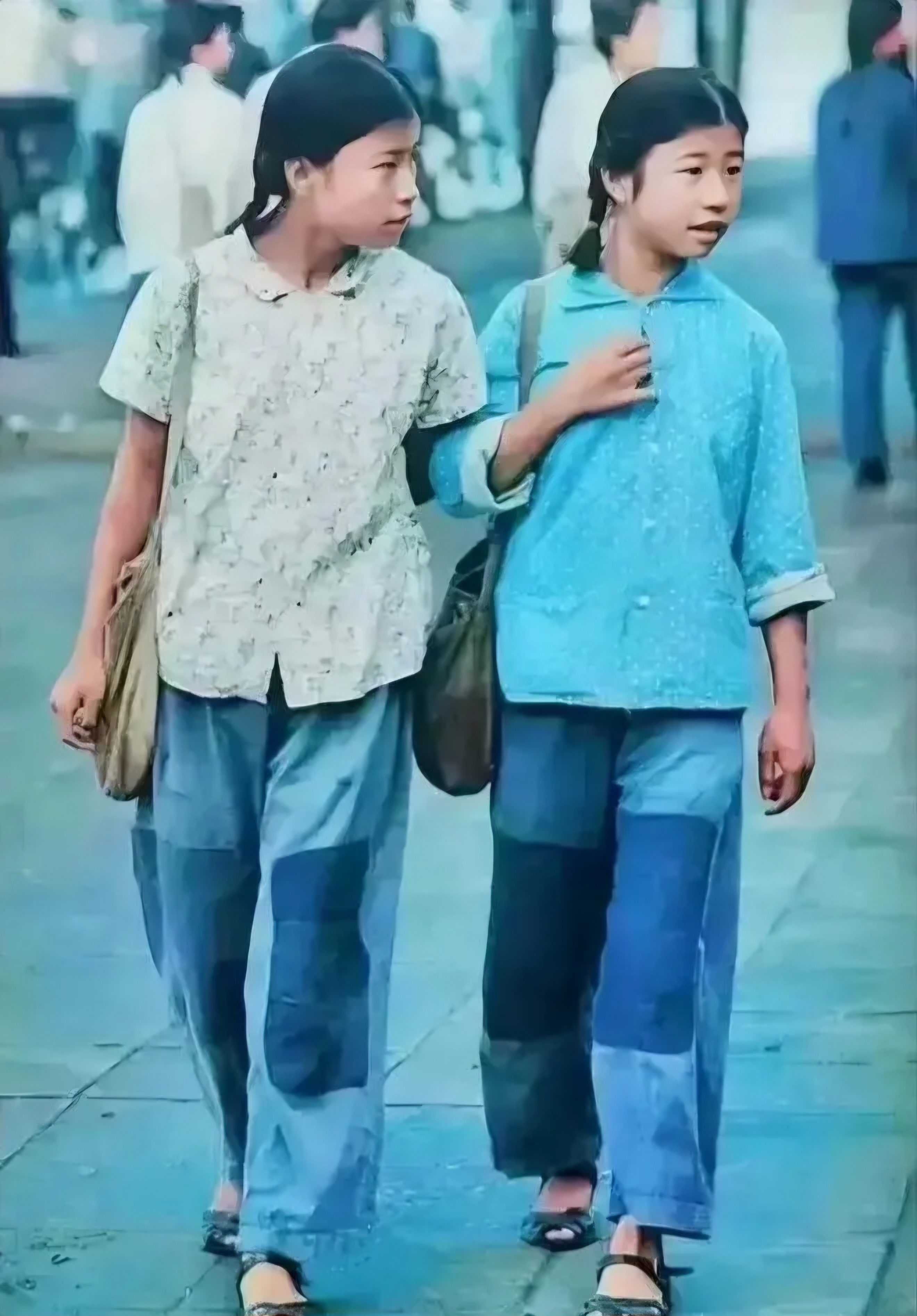 70年代,两位穿着打补丁裤子的女孩走在街道上,她们应该是同学或者是